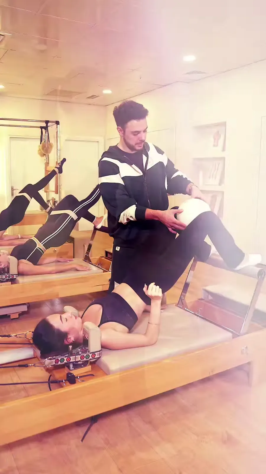 Eğitmen reformer üzerindeki sporcuya eşlik ediyor